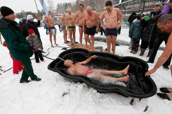 Winter swimming juga dijadikan ajang kumpul-kumpul bagi para orang tua. Mereka akan menyiram tubuh mereka terlebih dahulu di bathtube yang sudah disediakan (Ilya Naymushin/Reuters)