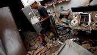 Seorang penduduk yang terluka memindahkan barang dari sebuah rumah yang hancur di Juchitan. (REUTERS/Edgard Garrido)