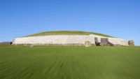 Inilah Newgrange, pemakaman kuno berupa bundaran dengan beratapkan rumput hijau, yang membuatnya terlihat seperti piring terbang yang sedang mendarat (Thinkstock)