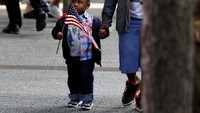 Seorang anak laki-laki membawa bendera Amerika di National 9/11 Memorial and Museum (REUTERS/Brendan McDermid)