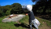 Kuburan masal ini berbentuk seperti sumur besar yang cukup dalam. Seorang grave cleaner akan membawa meletakkan tumpukan mumi tersebut di dalam kuburan masal (Jorge Dan Lopez/Reuters)