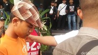 Dodik tampak mengenakan kaos berwarna oranye dan topi kotak-kotak begitu tiba di Bandung