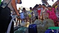 Anggota Kepolisian Polres Banyuwangi membagikan air bersih menggunakan mobil water cannon di Desa Sidodadi, Wongsorejo, Banyuwangi, Jawa Timur, Selasa (12/9). Bantuan air bersih tersebut disalurkan kepada masyarakat setempat yang kesulitan mendapatkan air bersih sejak bulan juli akibat musim kemarau panjang. (Foto: ANTARA FOTO/Budi Candra Setya)
