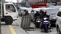 Pengendara sepeda motor menghindari bekas galian di tengah kemacetan.