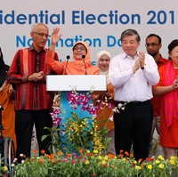 Busana Halimah tampak serasi dengan sang suami Mohammed Abdullah Alhabshee yang mengenakan kemeja tenun dengan gradasi warna oranye-merah. Foto: REUTERS/Edgar Su
