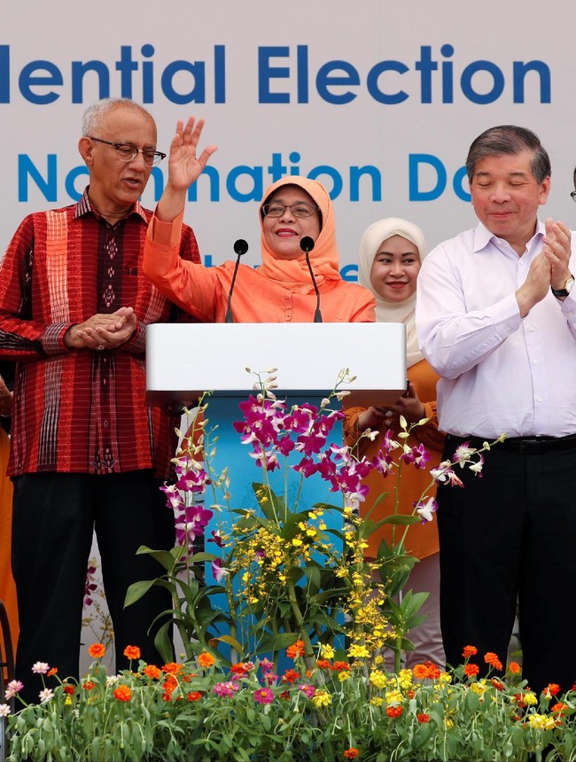 Busana Halimah tampak serasi dengan sang suami Mohammed Abdullah Alhabshee yang mengenakan kemeja tenun dengan gradasi warna oranye-merah. Foto: REUTERS/Edgar Su