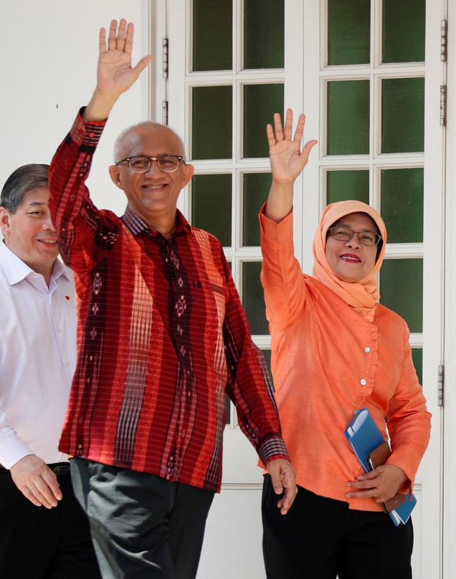 Halimah Yacob memadankan blouse dan hijab oranye dengan celana hitam klasik. Hitam merupakan warna aman yang bisa dipadupadankan dengan warna busana apapun, yang bold sekalipun. Foto: Reuters
