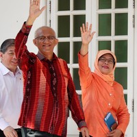 Halimah Yacob memadankan blouse dan hijab oranye dengan celana hitam klasik. Hitam merupakan warna aman yang bisa dipadupadankan dengan warna busana apapun, yang bold sekalipun. Foto: Reuters