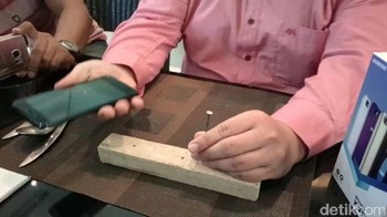 Evercoss pun coba membuktikan kekuatan layar Kingkong ini. Sebuah paku beton pun dipersiapkan di atas meja. Foto: Yudhianto/detikINET