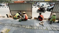Para pekerja merampungkan pembangunan pedestrian.