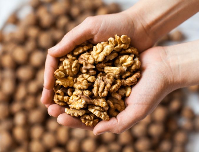 Walnuts with wooden spoon on background