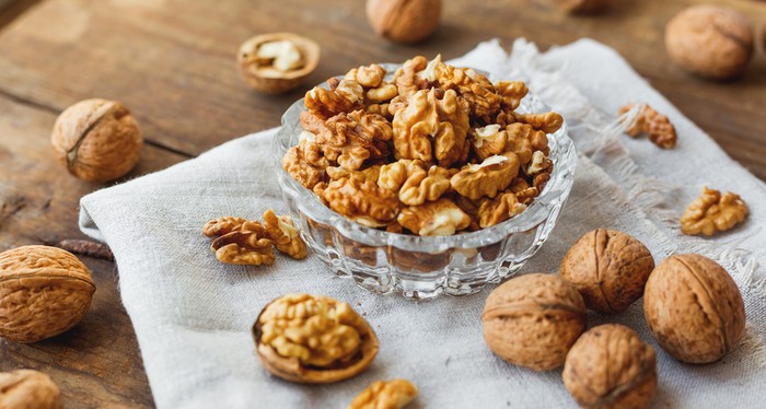Walnuts with wooden spoon on background