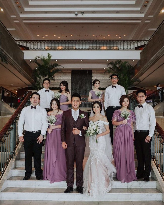 Stella Cornelia Winarto yang merupakan anggota JKT 48 menikah dengan pesinetron Fendi Chow. Dalam pernikahannya, para bridesmaid menggunakan gaun ungu dengan aksen draperi yang cantik. Foto: Instagram