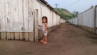 Seorang gadis kecil tengah berdiam diri disisi jalan pada 20 Agustus 2015 di Tumangang, Korea Utara usai  kedua negara bersitegang dan mencapai kesepakatan untuk mengurangi ketegangan setelah terjadi pertukaran tembakan artileri ke perbatasan demiliterisasi. (Foto oleh Xiaolu Chu/Getty Images)  