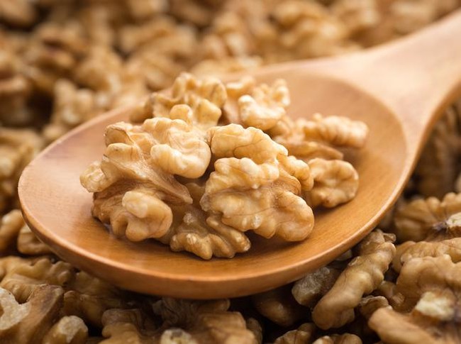 Walnuts with wooden spoon on background