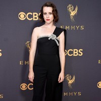 Claire Foy hadir dalam busana yang mencuri perhatian, yakni jumpsuit hitam berpotongan tegas dari Oscar de la Renta. Tampilan jumpsuit yang terkesan edgy tampak anggun memikat dengan embroidery kristal dan long cape di satu sisi. Foto: Dok. Getty Images