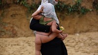 Seorang pengungsi Rohingya membawa bayinya saat hujan di sebuah kamp di Coxs Bazar, Bangladesh pada 18 September 2017. REUTERS / Danish Siddiqui