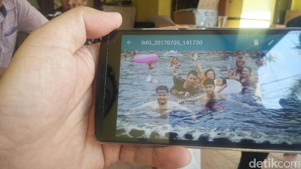 Ayah Eko menunjukkan foto kenangan bersama anaknya saat berlibur. 