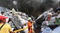 Petugas menyiram barang-barang bekas agar tidak ikut terbakar.