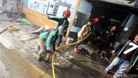 Driver ojek online membantu petugas Damkar memadamkan api yang membakar rumah, pabrik roti, dan toko percetakan, Selasa (19/9/2017).