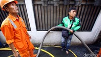Driver ojek online rela basah-basahan untuk memadamkan api.
