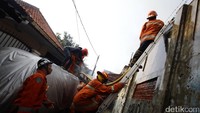 Petugas pemadam memanjat rumah warga untuk menjangkau titik api.