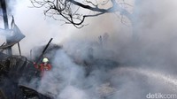 Di antara puing-puing, petugas berjibaku memadamkan api.