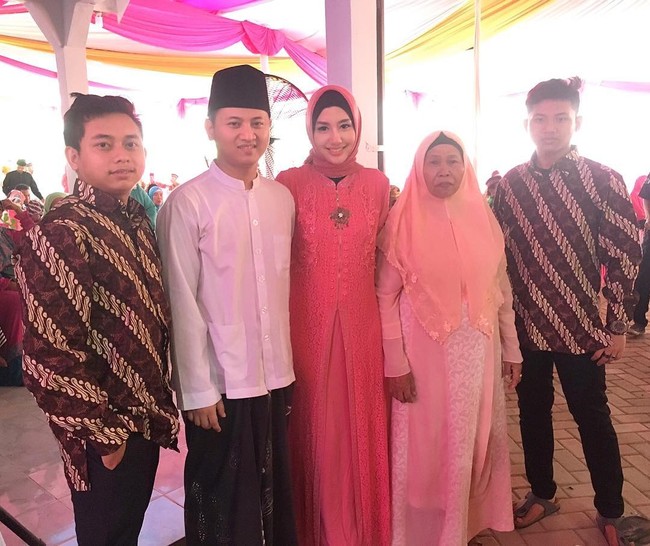 Tampaknya Novita Hardini suka berpenampilan anggun memakai sentuhan merah muda. Kali ini gamis panjang berpotongan kerah shanghai menjadi pilihan. Foto: Dok. Instagram @novitamochamad