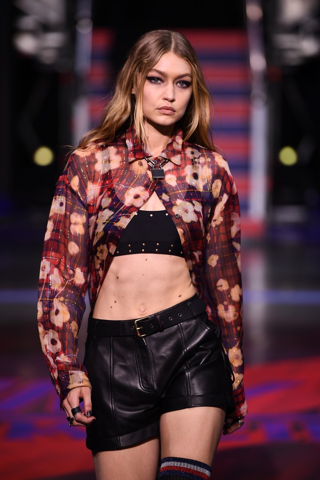 Di penampilan kedua, Gigi Hadid tampil edgy sekaligus seduktif dengan padanan crop tops, leather pants dan blouse transparan motif floral. Foto: Getty Images
