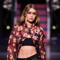 Di penampilan kedua, Gigi Hadid tampil edgy sekaligus seduktif dengan padanan crop tops, leather pants dan blouse transparan motif floral. Foto: Getty Images
