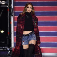 Gigi Hadid tampil sebagai pembuka show koleksi ketiga kolaborasi Tommy x Gigi, mengenakan croptop dan short denim pants yang dipadu coat tartan panjang. Foto: Getty Images