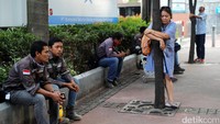 Dua orang aktivis dari Koalisi Pejalan Kaki memeluk pohon di depan warga yang sedang duduk-duduk di depan taman.