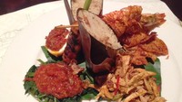 Dalam menu Nasi Campur Bali dengan Udang di Roemah Rempah, nasi bakar dibungkus daun hanjuang. Nasi diberi sentuhan Bali dengan pelengkap ayam sisit, kering kentang, plecing kangkung, sate lilit, udang bakar dan telur sambal. Komplet!