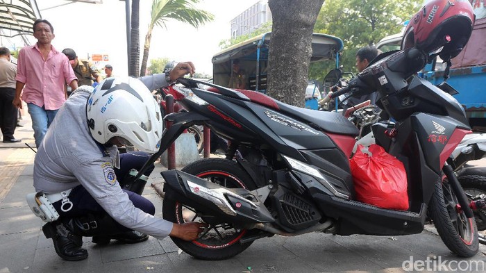 Petugas gabungan Dishub dan Satpol PP menertibkan kendaraan yang nekat parkir di trotoar dengan sanksi cabut pentil di Jl Kramat Raya, Jakarta.