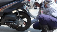 Petugas mencabut pentil sepeda motor yang parkir di trotoar.