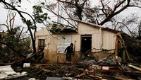 Seorang pria mencari barang berharga di rumah kerabatnya yang rusak (REUTERS/Carlos Garcia Rawlins)