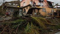 Orang-orang beristirahat di luar rumah yang rusak setelah daerah itu terkena Badai Maria di Yabucoa, Puerto Riko. (REUTERS/Carlos Garcia Rawlins)