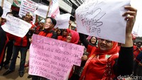 Mantan pegawai 7-Eleven berorasi sambil membentangkan poster tuntutan.