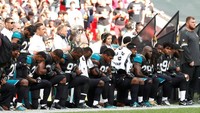 Para pemain Jacksonville Jaguars berlutut dan bergandengan tangan saat lagu kebangsaan AS dinyanyikan sebelum pertandingan melawan Baltimore Ravens di Wembley, London.