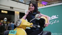 Seorang model berpose di atas Vespa GTS 300.