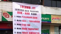 Mantan pegawai 7-Eleven memasang spanduk tuntutan di depan PT Modern Internasional Tbk (MDRN) selaku induk usaha dari PT Modern Sevel Indonesia (MSI).