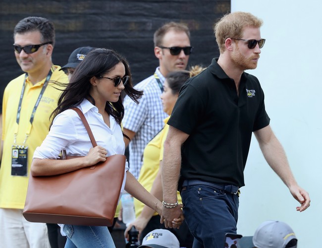 Meghan Markle tampil chic dengan padu padan yang tak pernah tampak membosankan, yakni kemeja putih dan celana jeans skinny. Aksesori seperti tote bag dan flat shoes yang nyaman dipilih Meghan untuk melengkapi penampilannya. Foto: Chris Jackson/Getty Images