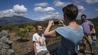 Beberapa turis bahkan sempat berfoto dengan latar belakang Gunung Agung. Ulet Ifansasti/Getty Images.