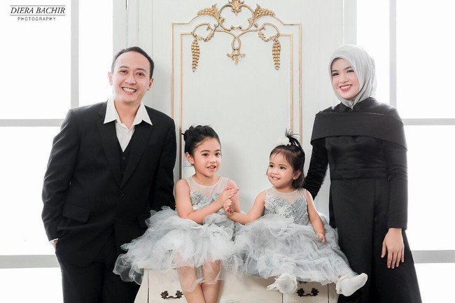 Aurora Kalista tampil cantik dengan dress hitam berbahan satin dove ketika pose untuk foto keluarga. Tema hitam-putih diambil kali ini. Gaya hijabnya terlihat simpel dengan cara yang konvensional hanya menggunakan satu jarum pentul di bawah dagu. Foto: Dok. Instagram @arurorakalista