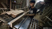 Seorang pekerja membuat kerajinan kayu.