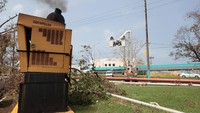 Mesin generator yang mengalami rusak sebagian berada di dekat orang yang tengah memperbaiki instalasi listrik
