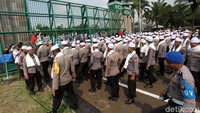 Aparat kepolisian yang mengenakan sorban dan peci berjaga dari dalam gedung DPR.