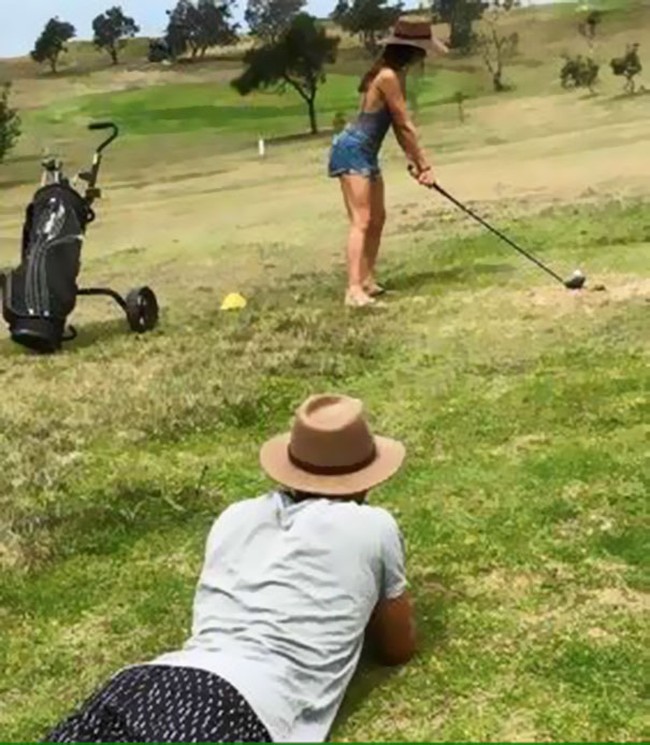 Sementara sang kekasih bergaya main golf, sang pria berbaring di rumput siap menjepretkan kamera. Foto: Dok. Bored Panda