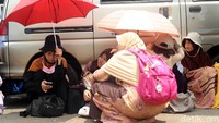 Sebagian dari mereka membawa payung untuk melindungi tubuh dari sinar matahari.