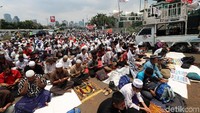 Peserta aksi telah duduk mendengarkan khotbah yang disampaikan melalui pengeras suara dari masjid samping DPR.